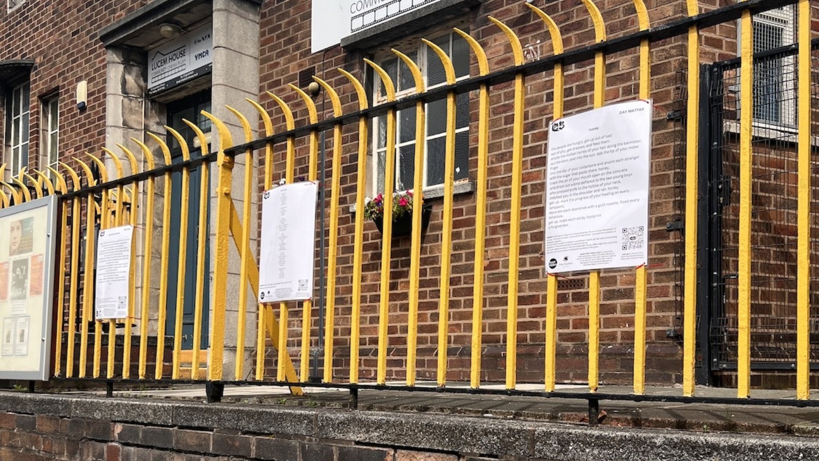 Three pieces of paper containing poems attached to yellow railings
