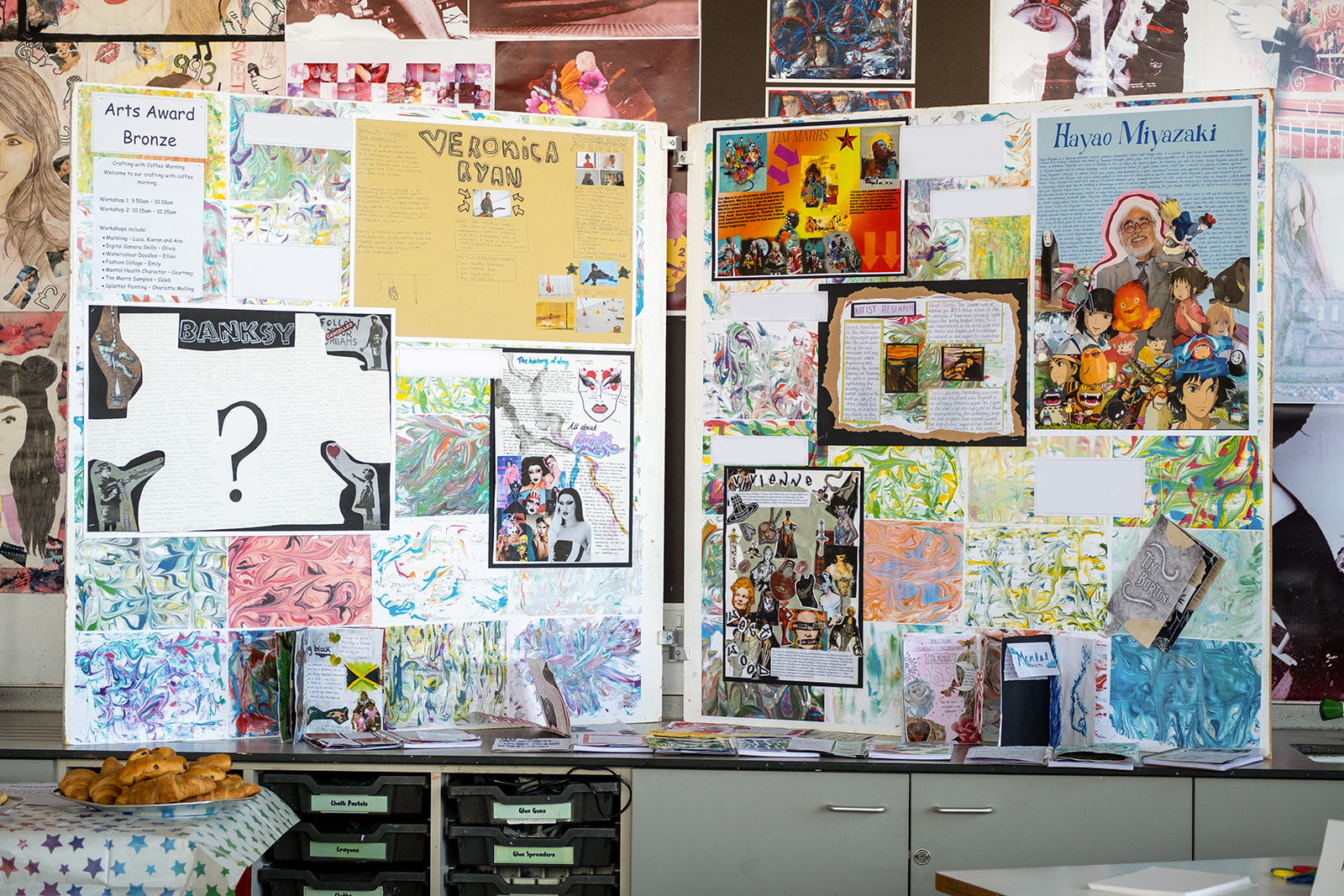 Artwork by young people displayed on a board in a classroom