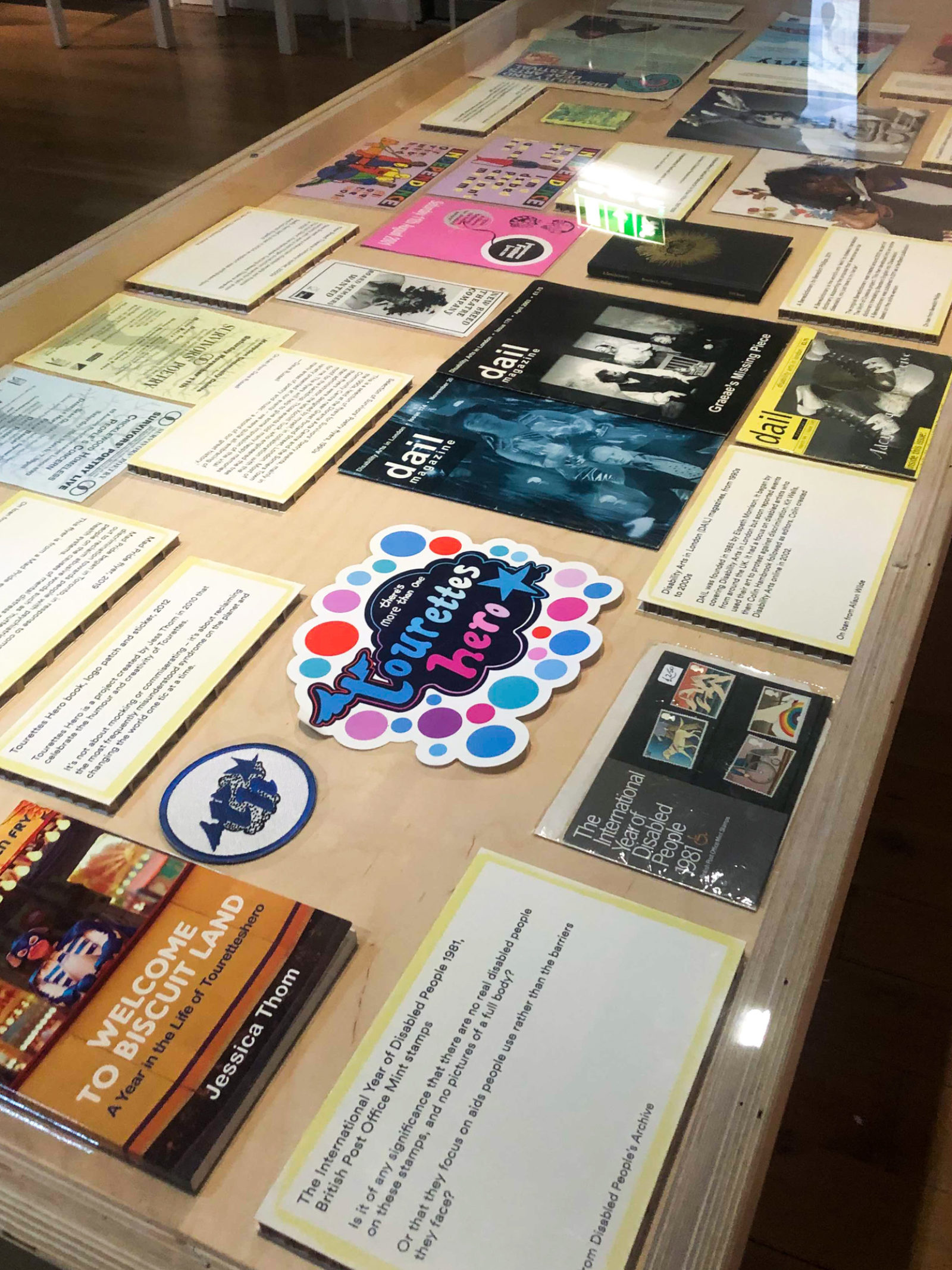 Printed material laid out in a glass case at the People's History Museum, the one in the centre reads 'the Tourettes hero'