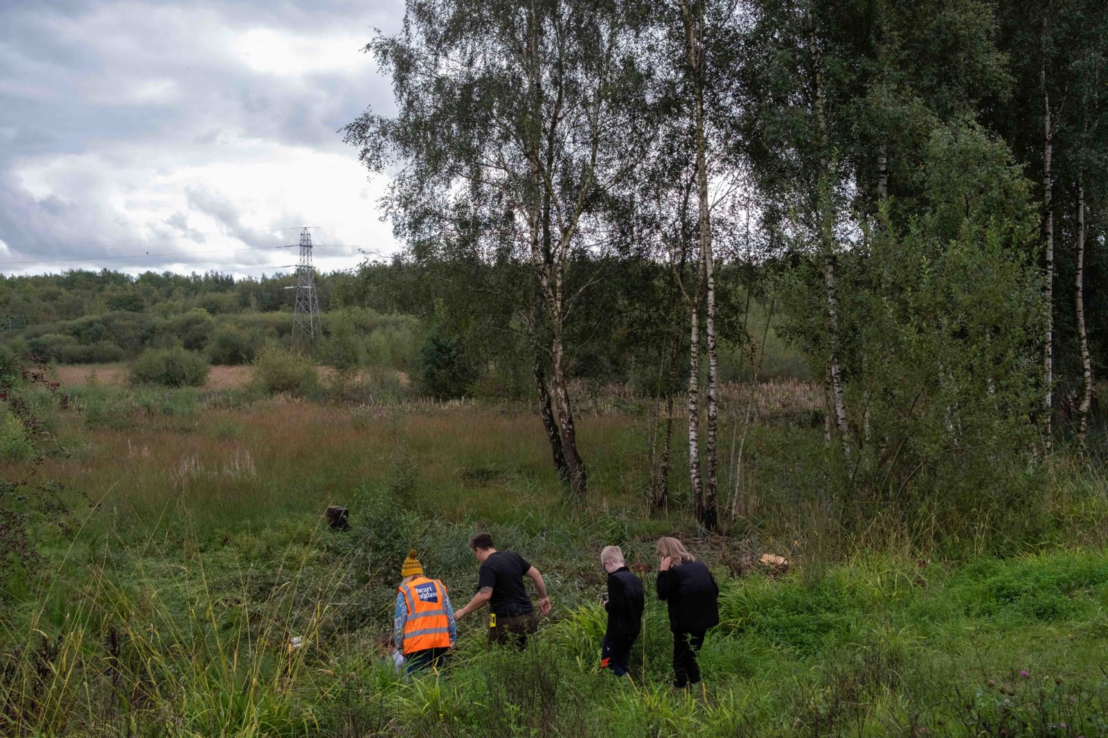 4 people, 2 adults and 2 children, walk down to the peatland in Colliers Moss.