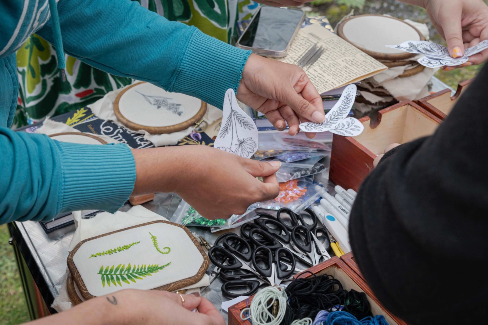 A woman's hands are photographed looking through the embroidery transfers.