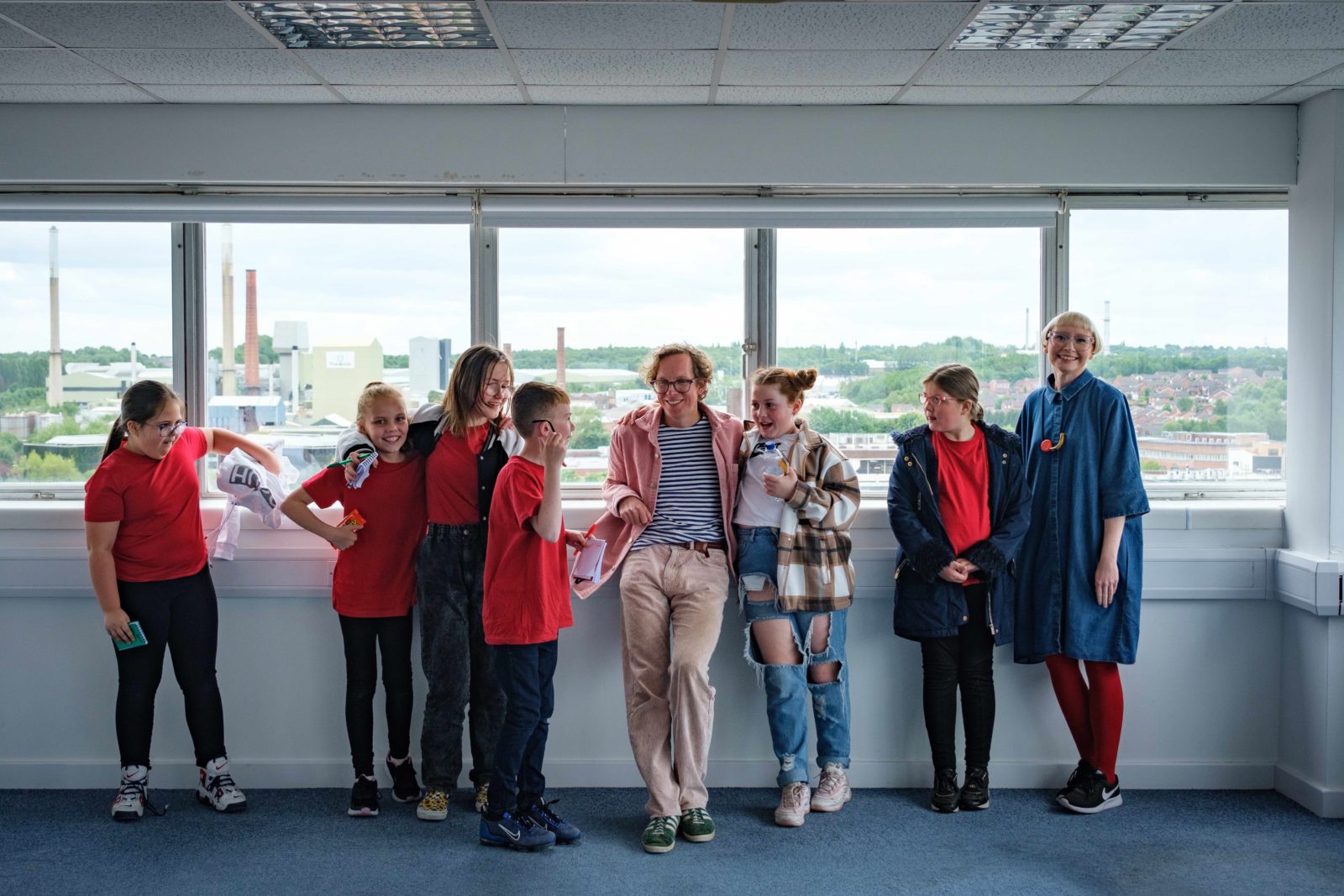 A group of people stand in front of a window looking over St Helens.