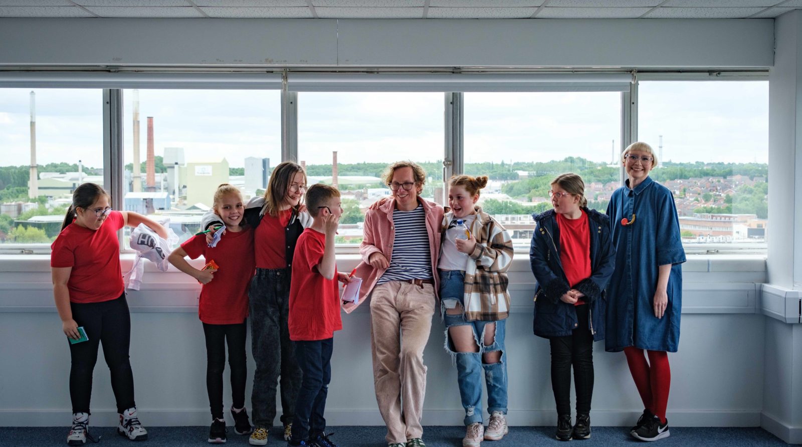 A group of people stand in front of a window looking over St Helens.