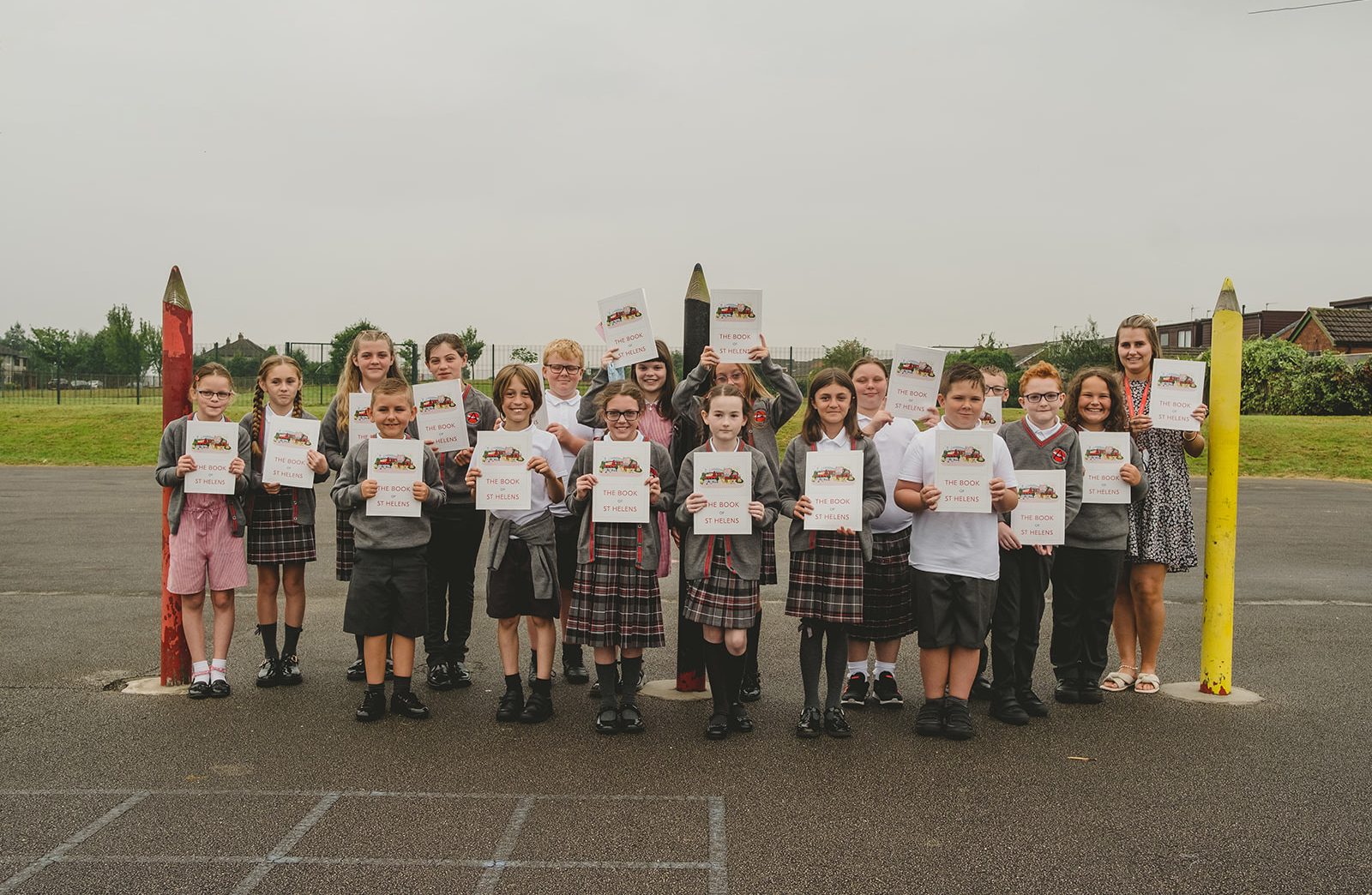 A class photo of year six at Ashurst Primary School. Each child and their teacher holds a copy of The Book Of St Helens