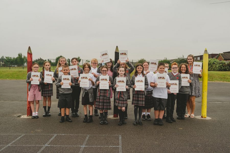 A class photo of year six at Ashurst Primary School. Each child and their teacher holds a copy of The Book Of St Helens