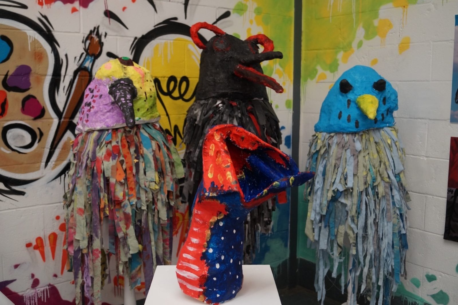 Brightly coloured papier mache sculptures of birds in an exhibition