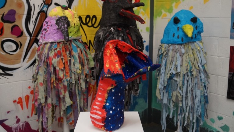 Brightly coloured papier mache sculptures of birds in an exhibition