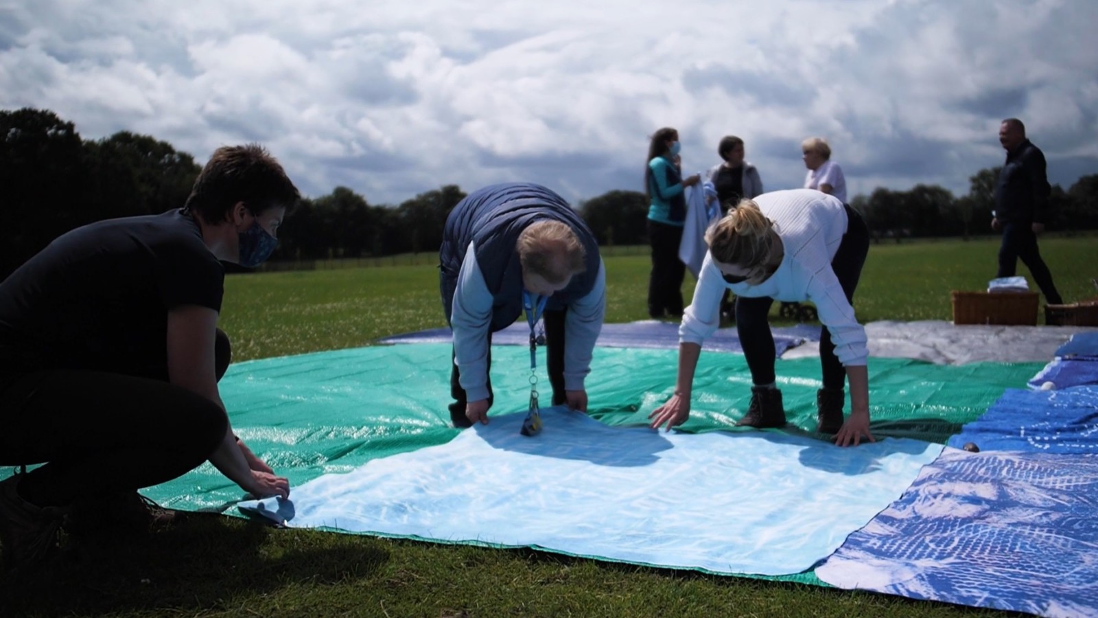 People laying blankets out on field.