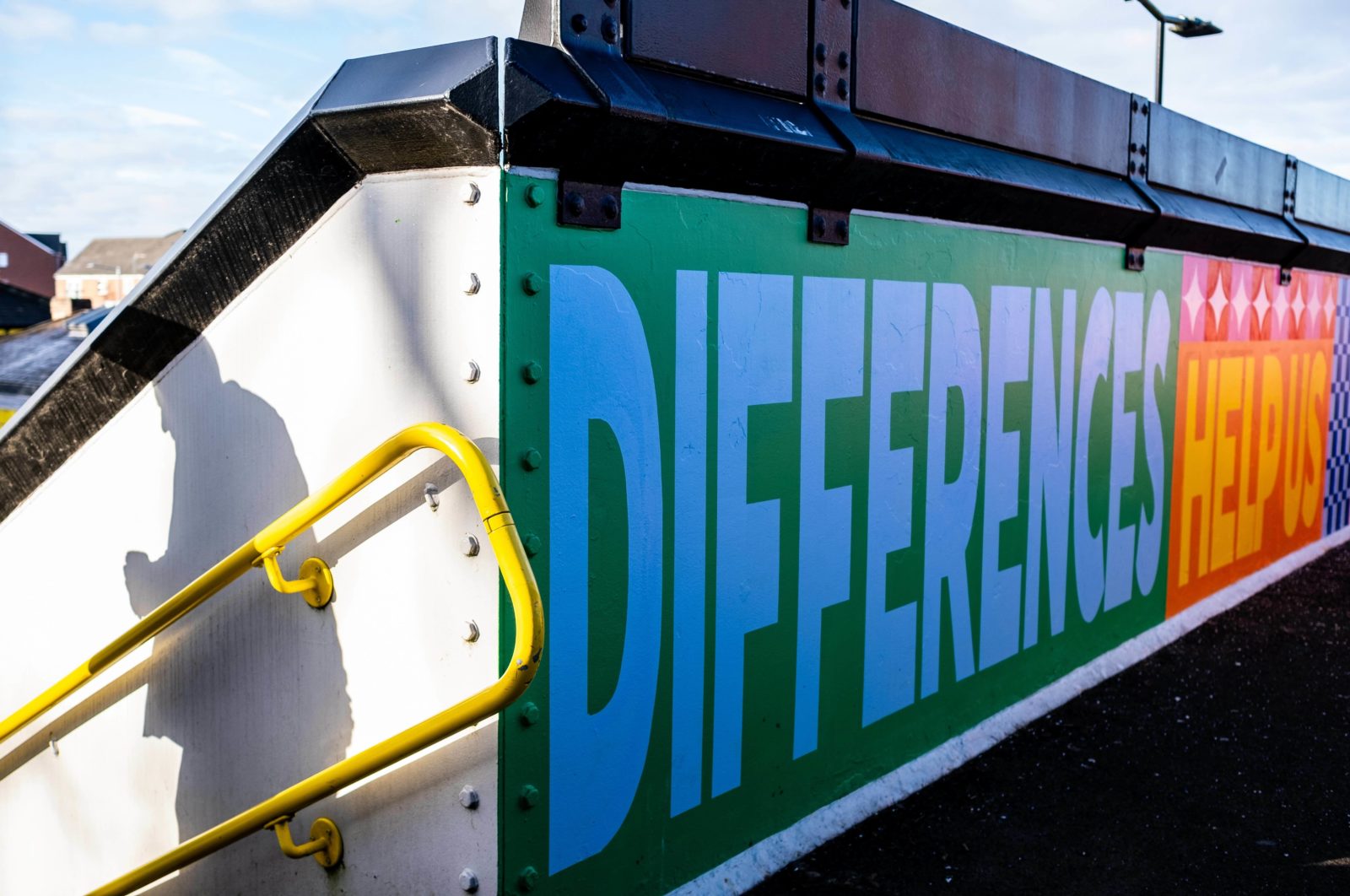 Part of the mural is photographed from up close, the words 'Differences help us' can be seen.