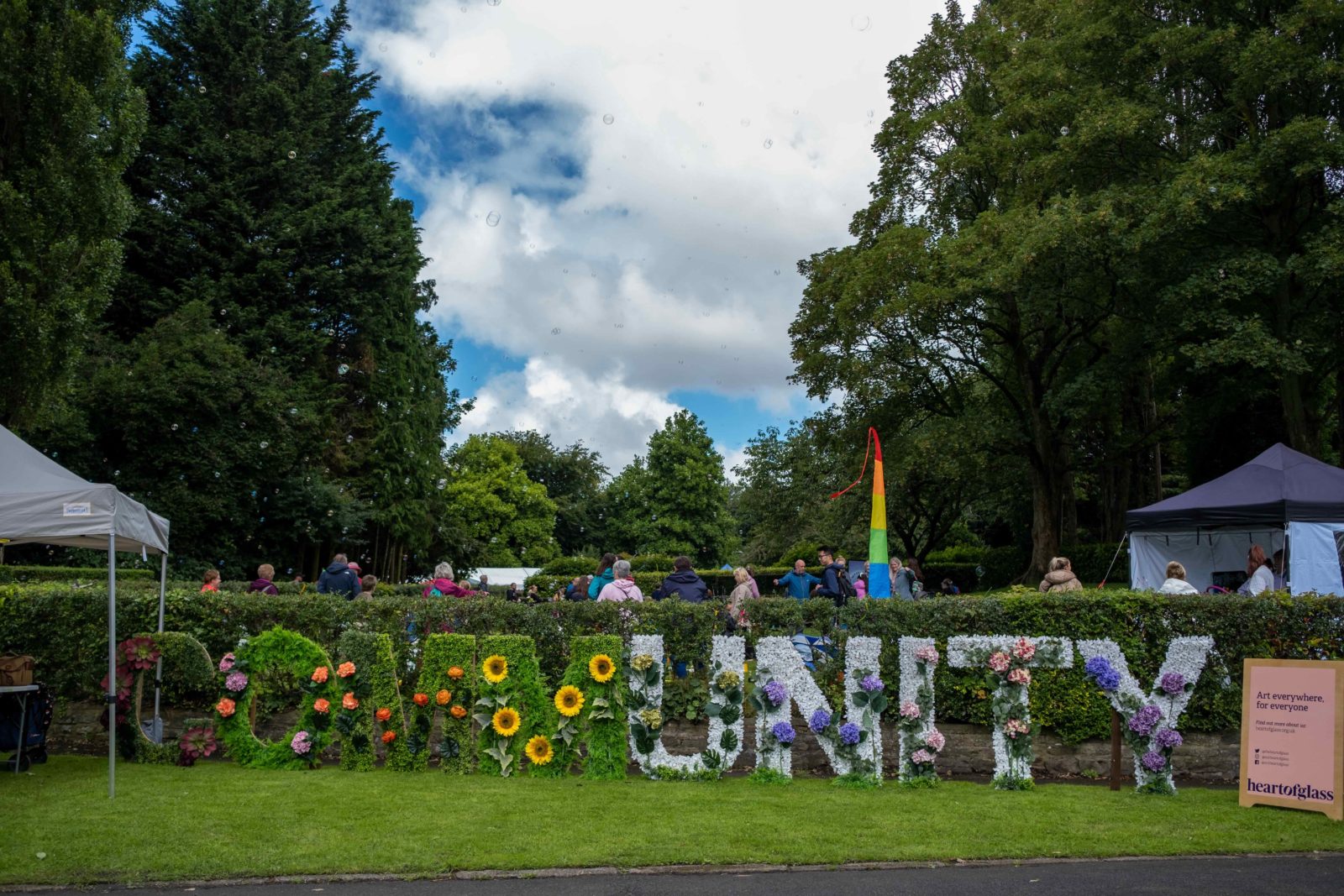 The word 'Community' is made out of artificial flowers and leaves, the 'unity' in community is in white and 'comm' is in green.