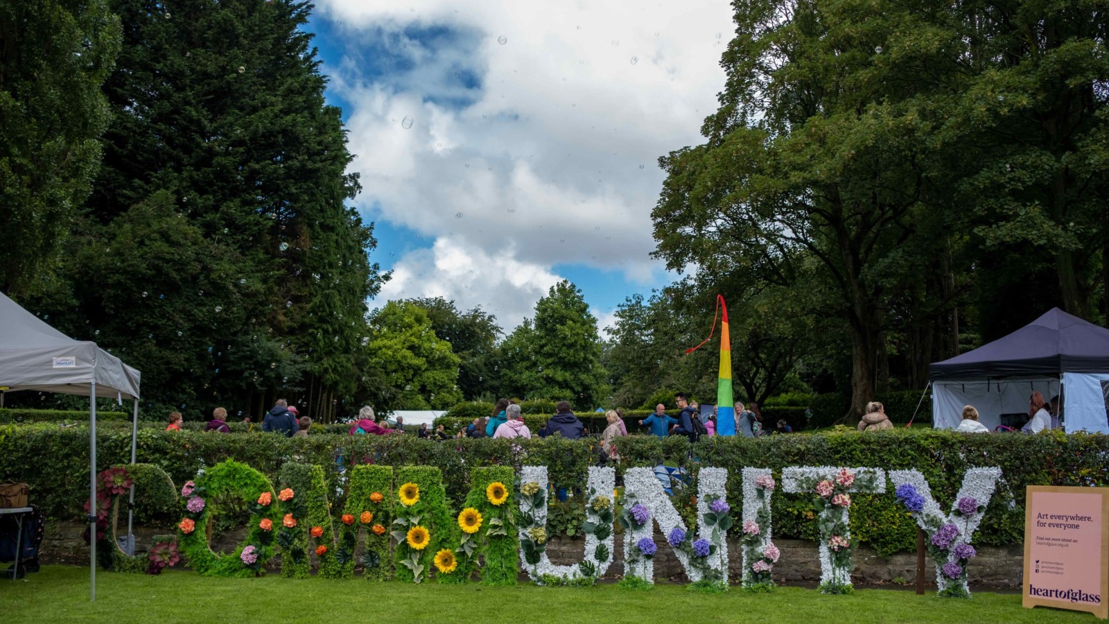 The word 'Community' is made out of artificial flowers and leaves, the 'unity' in community is in white and 'comm' is in green.