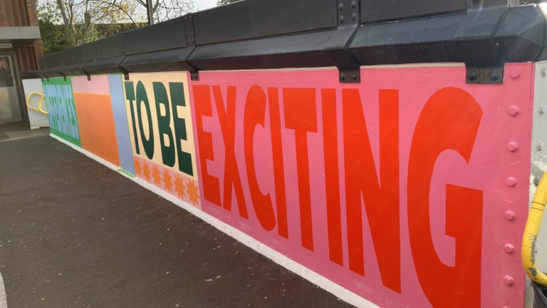 Photograph of an unfinished mural on a bridge that reads 'Differences to be exciting'.