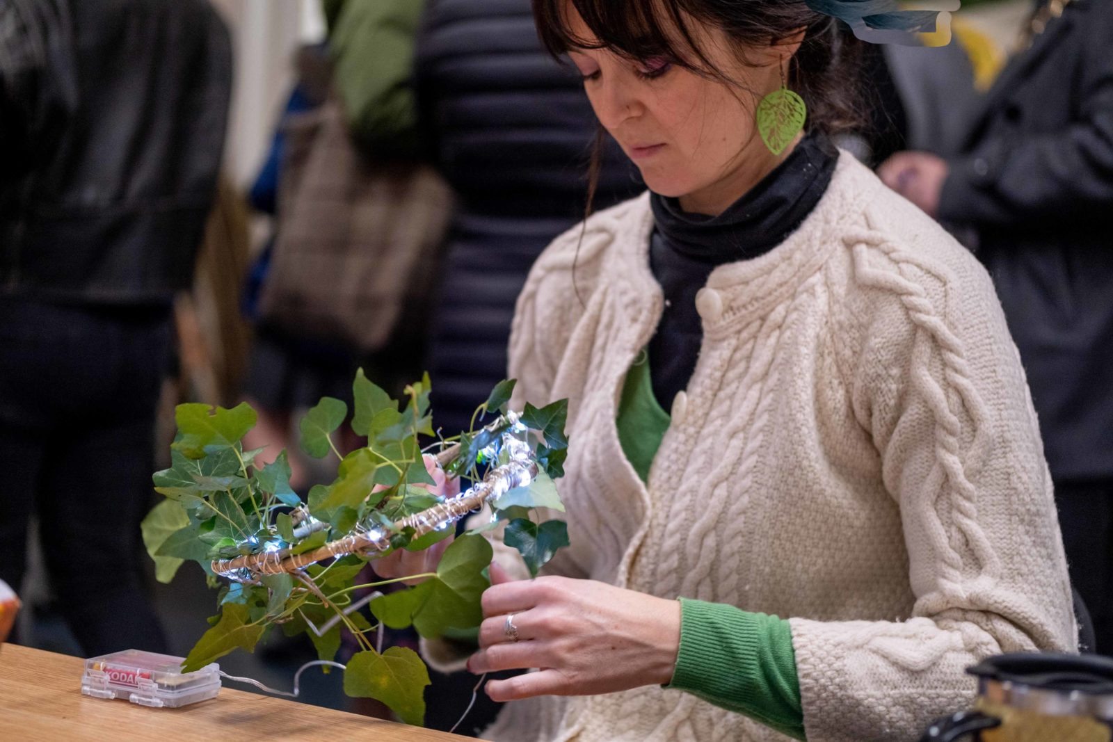 Workshop participant wrapping vines and lights around a round frame to make a wreath.