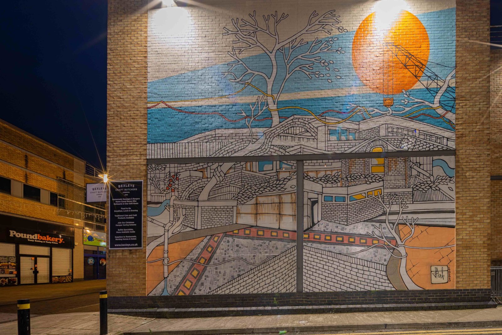 The Welcome Home mural by Jo Peel is photographed at night on Huyton High Street.