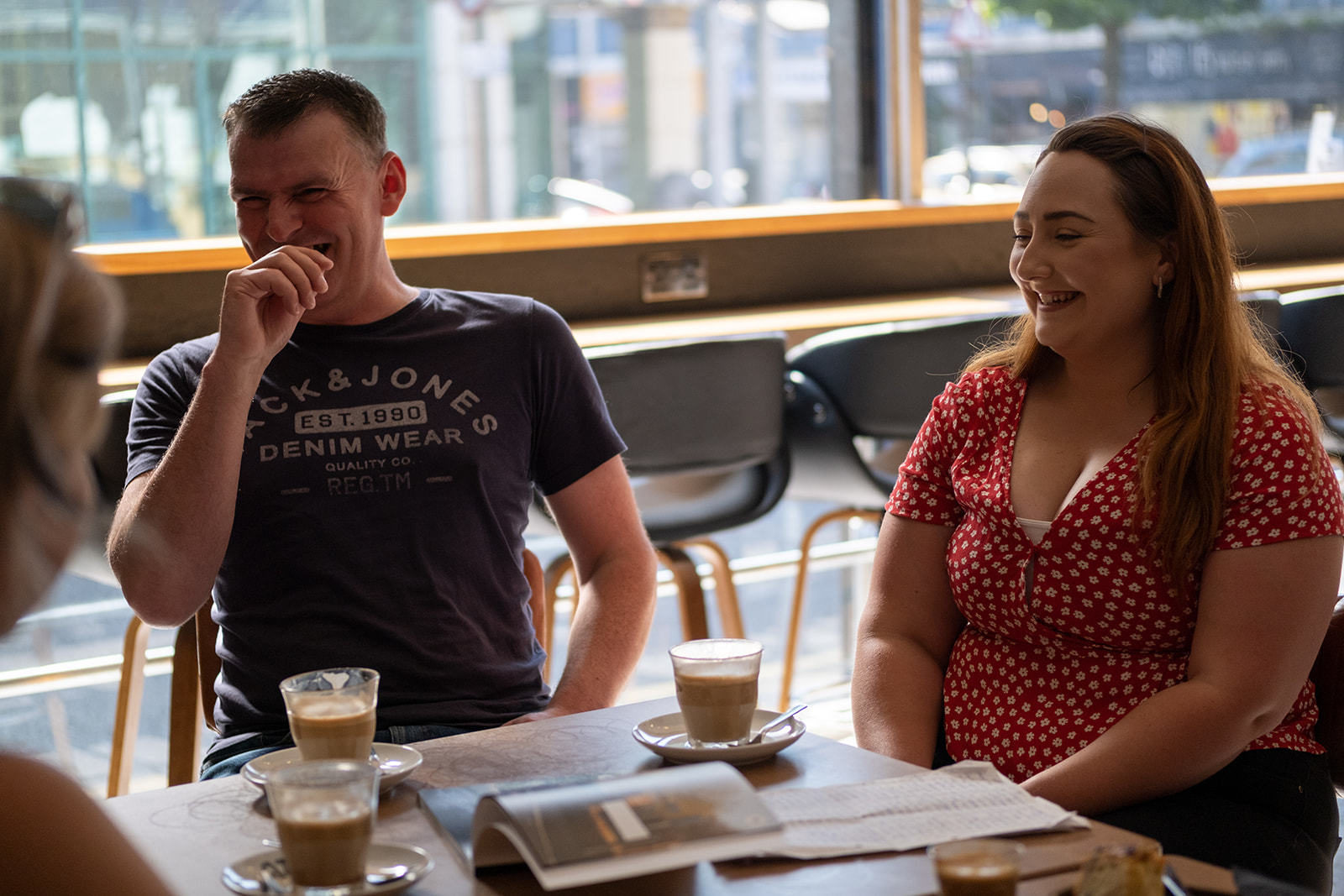 The couple that won the competition sit around a table at the coffee shop in the Bookstop laughing.