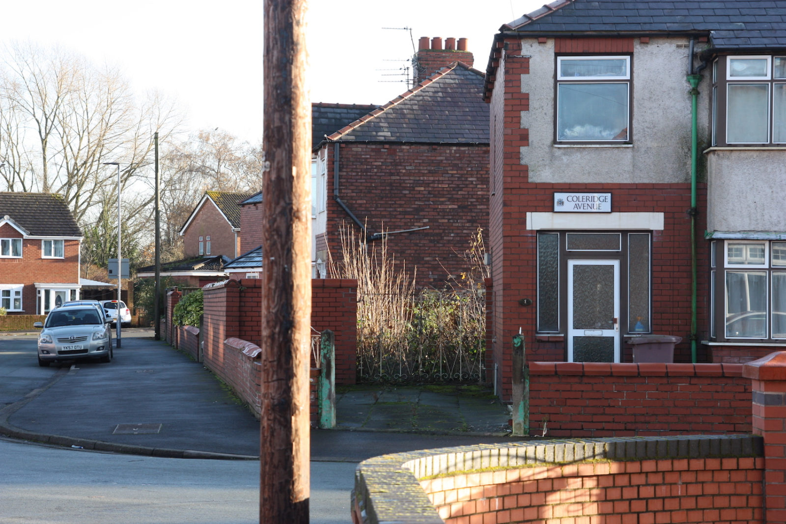 Coleridge Avenue sign is fitted above a front door of a concrete and red brick house.