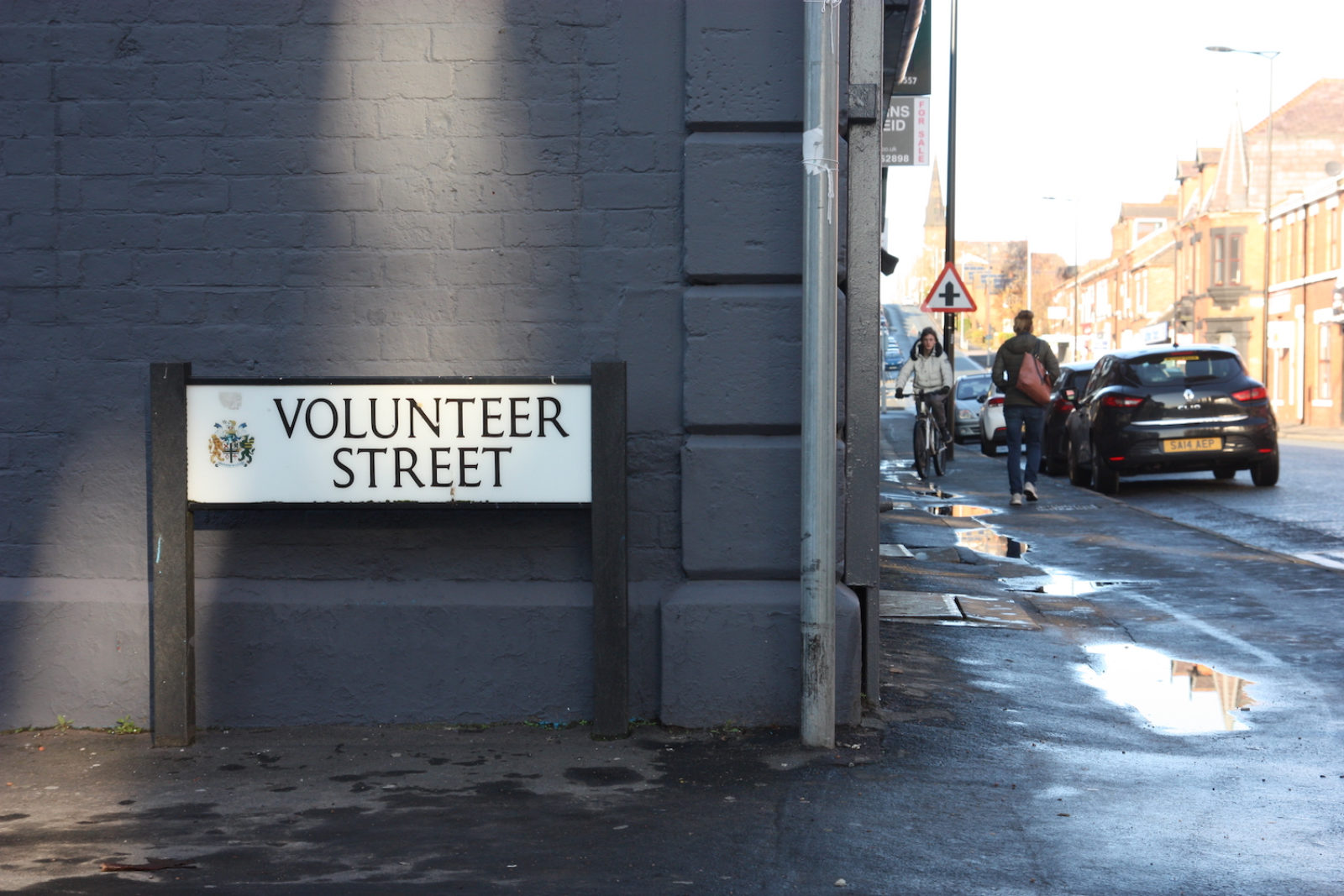 Volunteer Street sign is on the corner of a brick house that is painted dark grey.