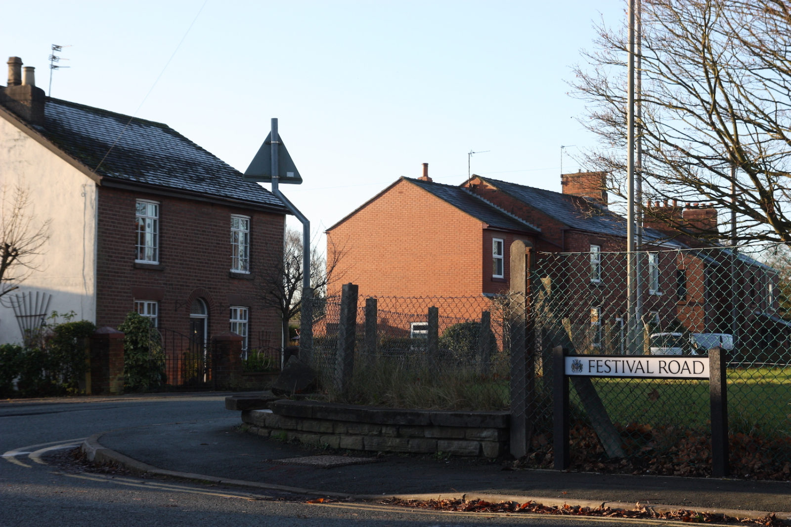 Festival Road is in front of wire fencing nd grass, there are semi detached houses in the backround.
