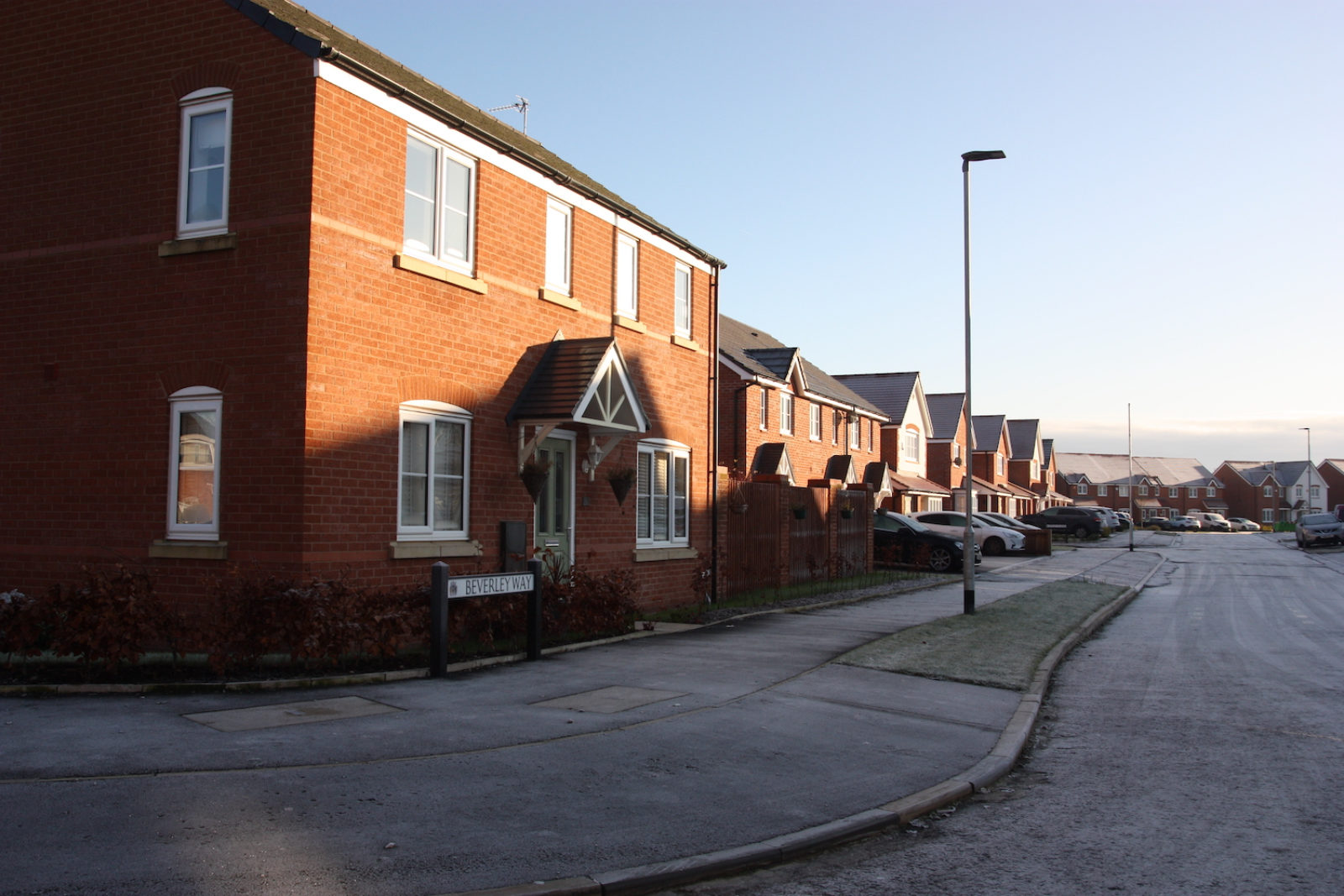 Beverley Way sign is in front of a new build redbrick house on a frosty street.