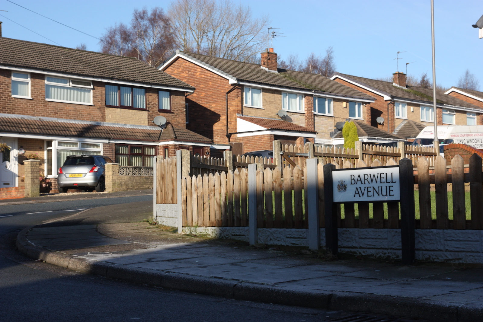 Barwell avenue is in front of a brown picket fence with semidetached houses behind it.