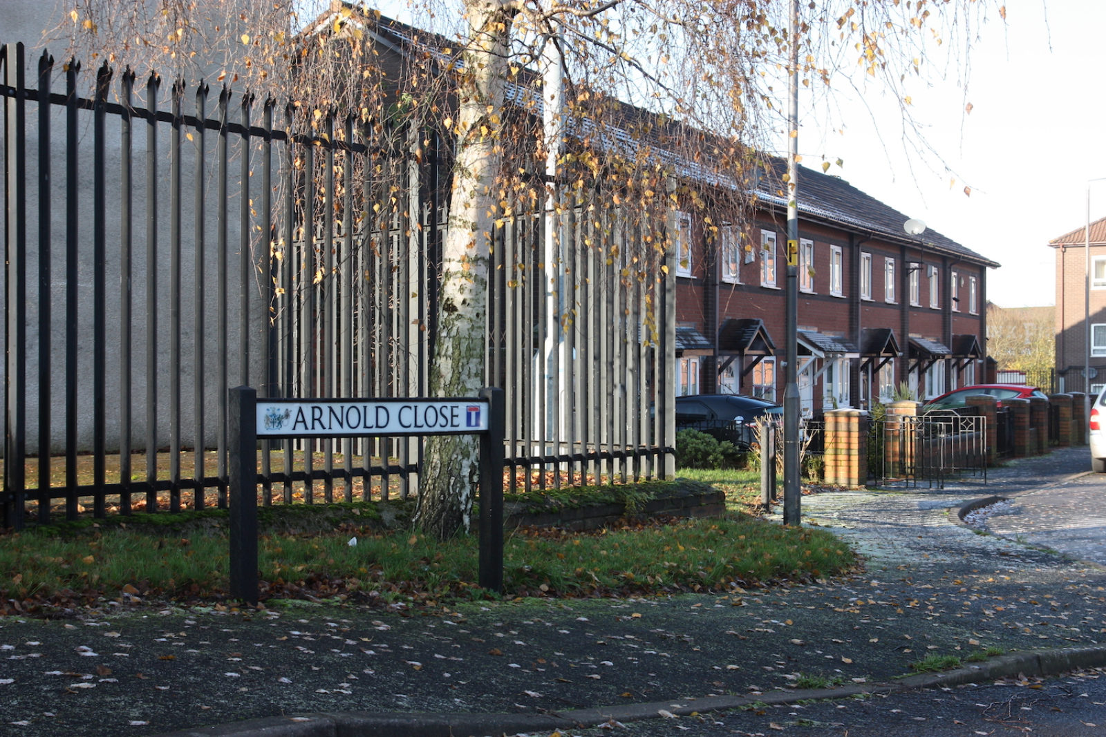 Arnold close sign is in front of a metal railing and an autumnal tree.