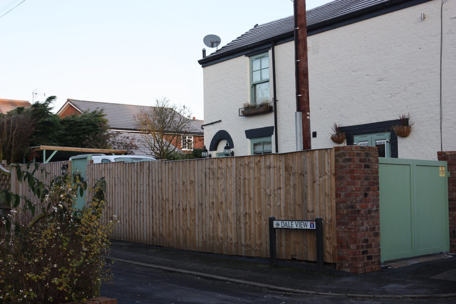Dale View Street sign is in front of a light brown wooden fence in front of a cream house.