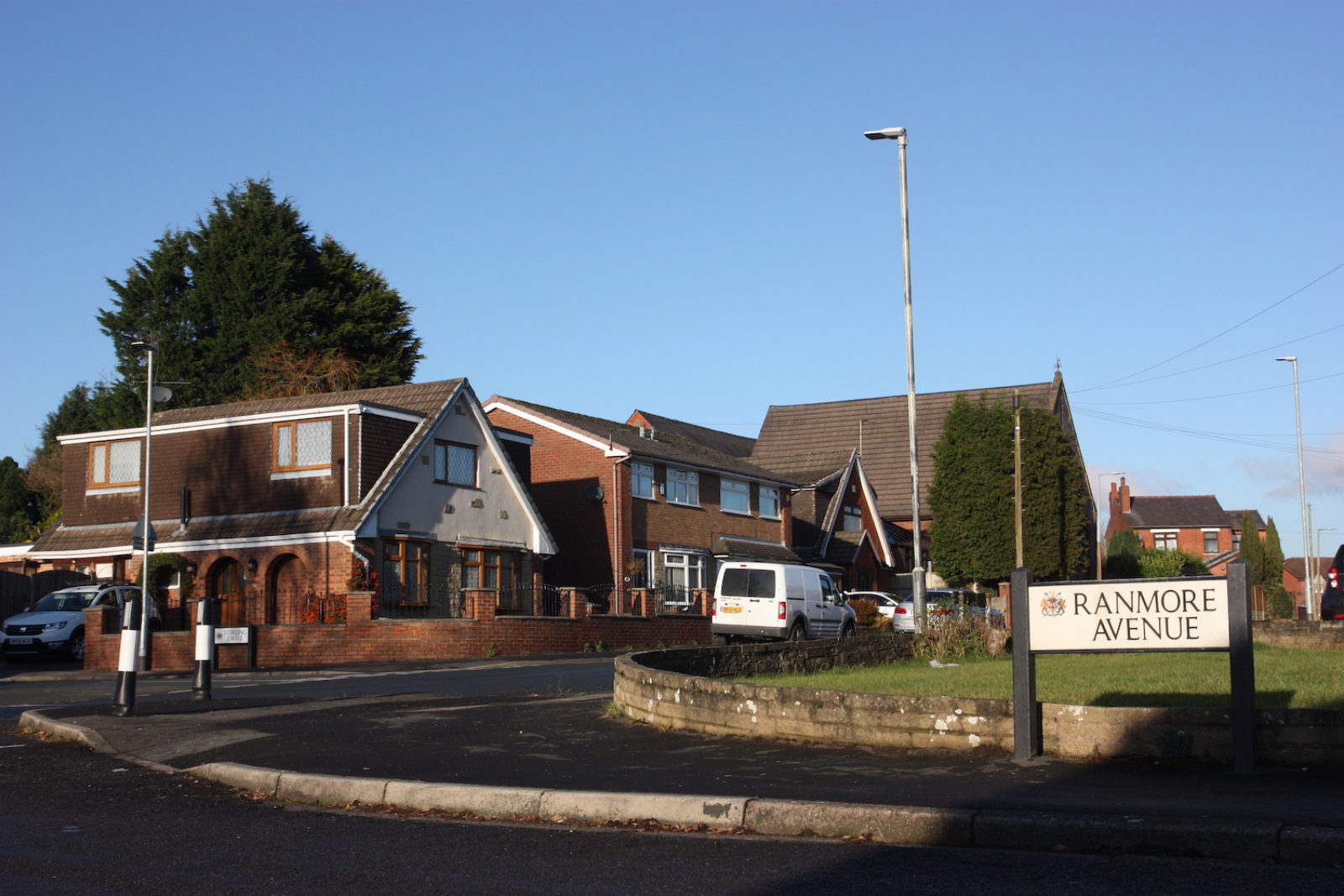 Ranmore Avenue sign is on a rounded patch of grass that is edged with a short grey wall.