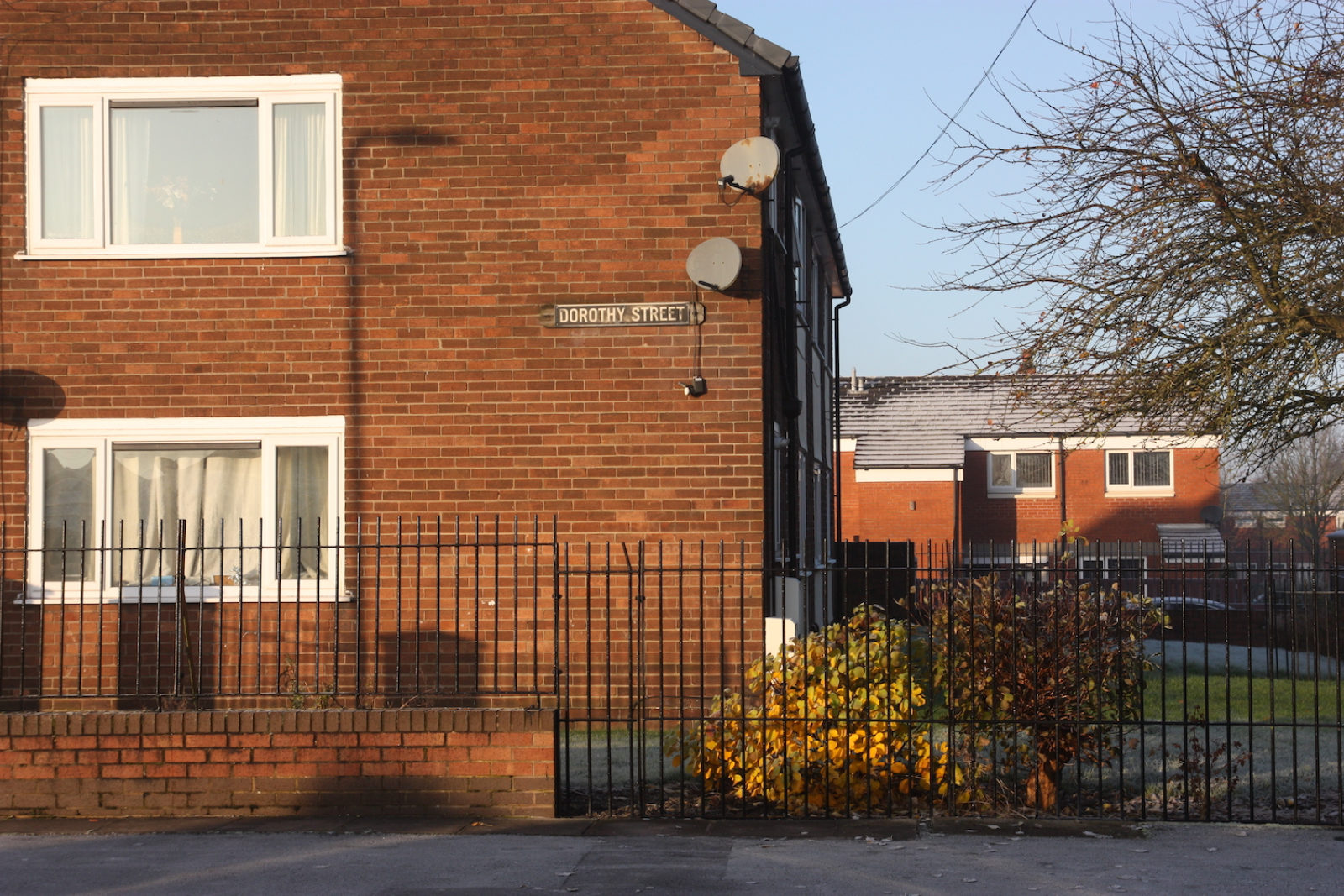 Dorothy Street sign is an old fashioned black and white one on the side of a redbrick house. The sun shines on the houses and there is frost on their roofs.