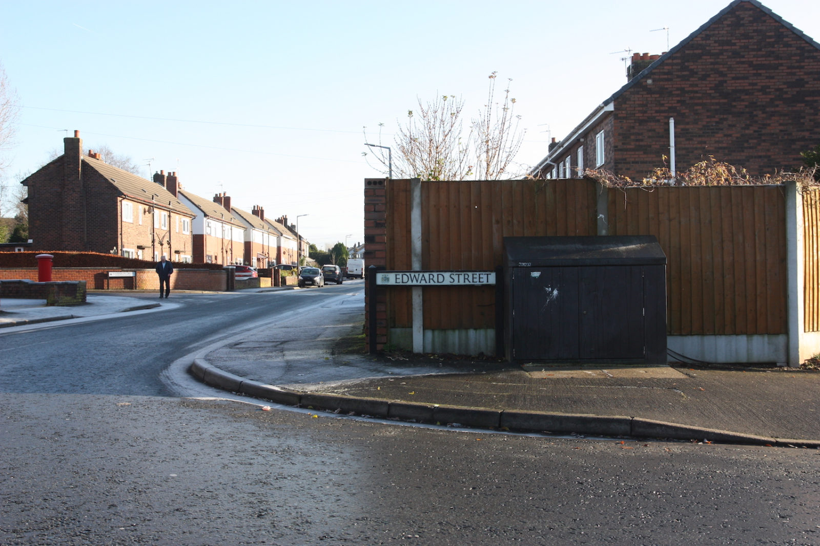 Edward Street sign is in front of a wooden fence and next to an electricity box.