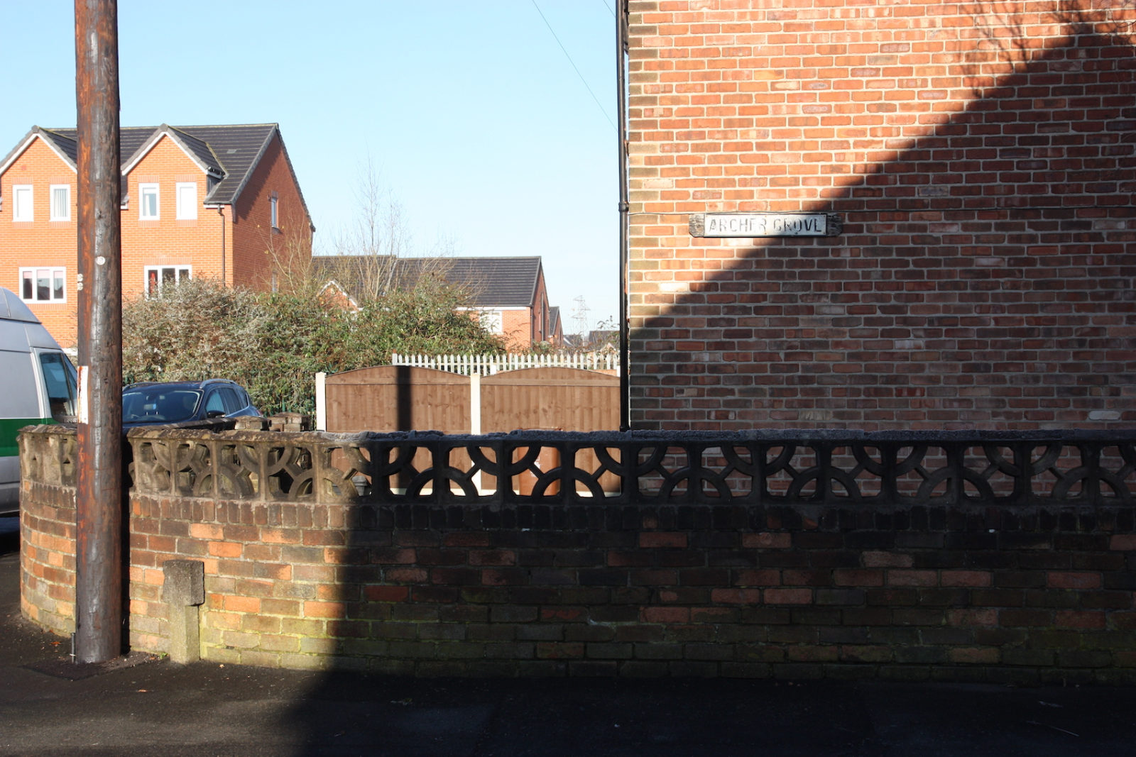 Archer Grove sign is on the side of a red brick house and looks old and worn, the letters are hard to decifer
