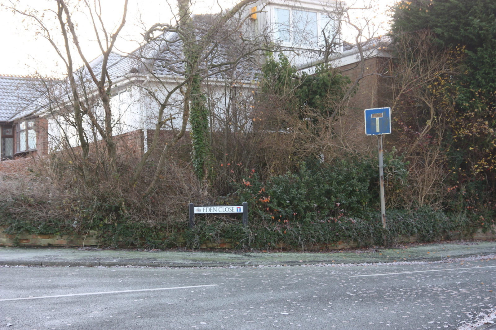 Eden Close sign is in front of trees, bushes and a White House.