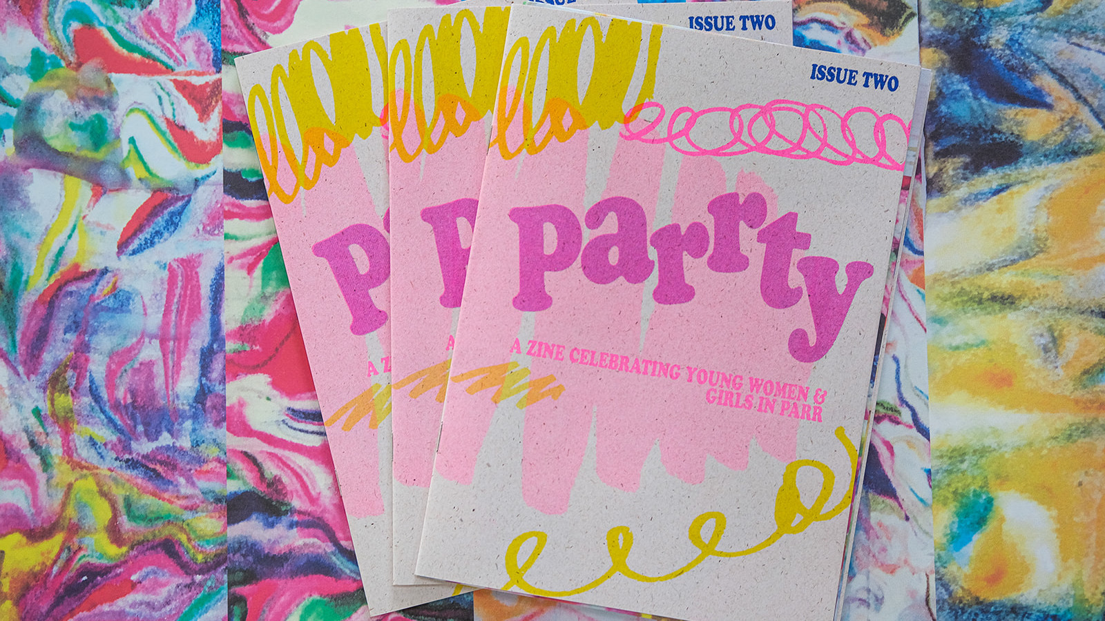 A fanned spread of issue two of PARRTY printed in popping colours of fluorescent pink, blue and yellow.