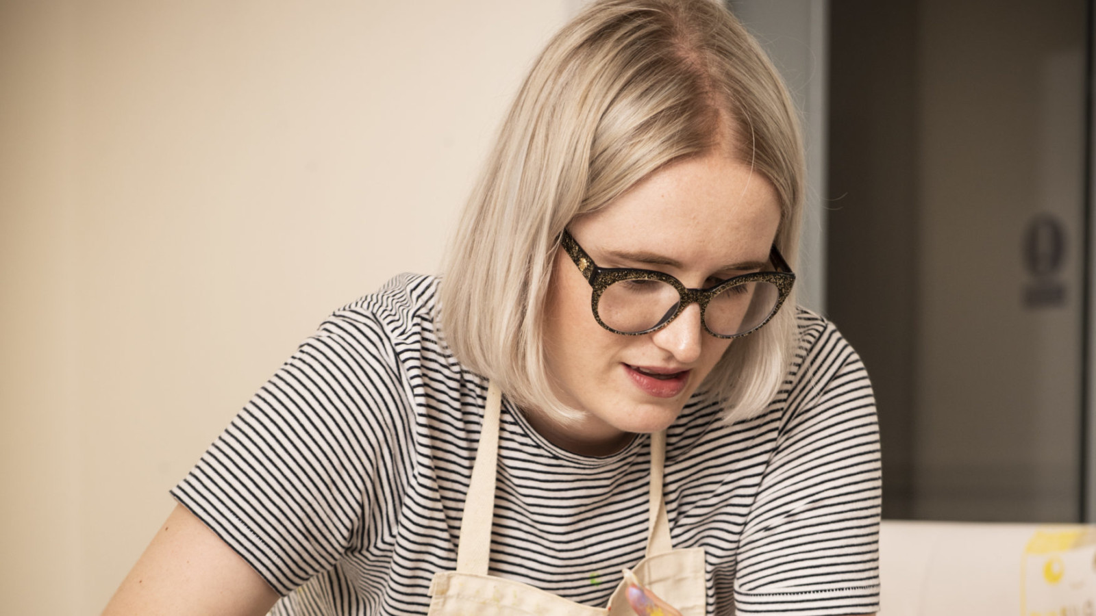 Artist Kate Hodgson wears an apron while screenprinting.