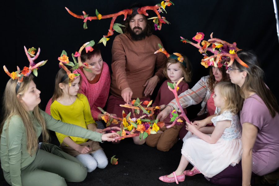 Group of children and adults sat in a circle wearing hand crafted antlers and holding antlers in the middle