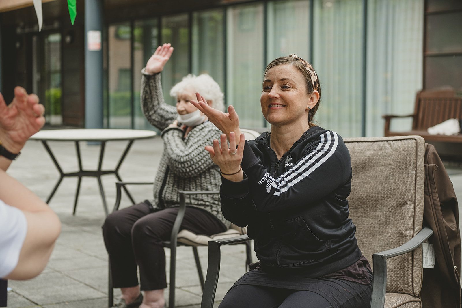 A woman in her forties demonstrates dance moves to a group of older people