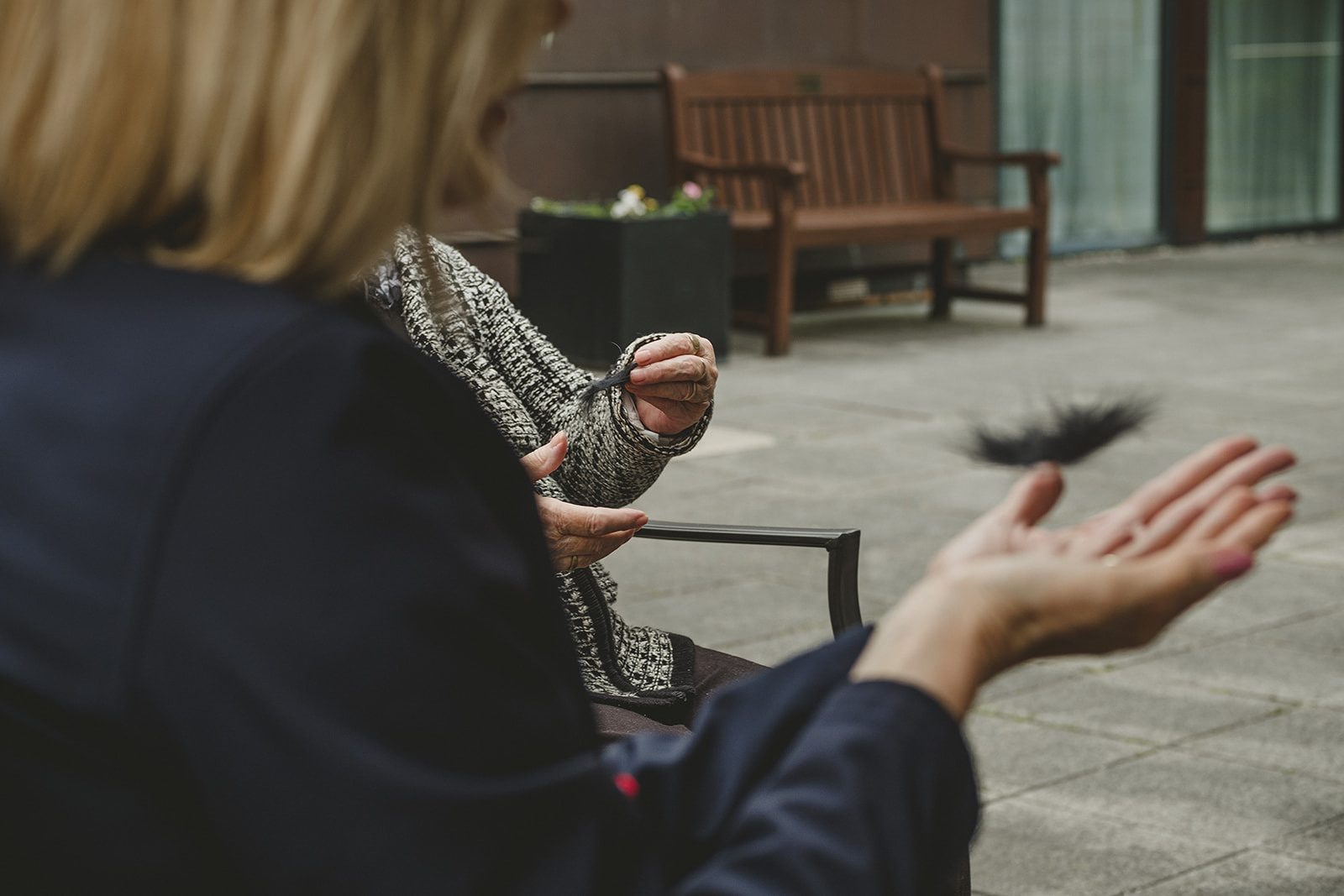 a woman holds out her hands to catch a falling black feather