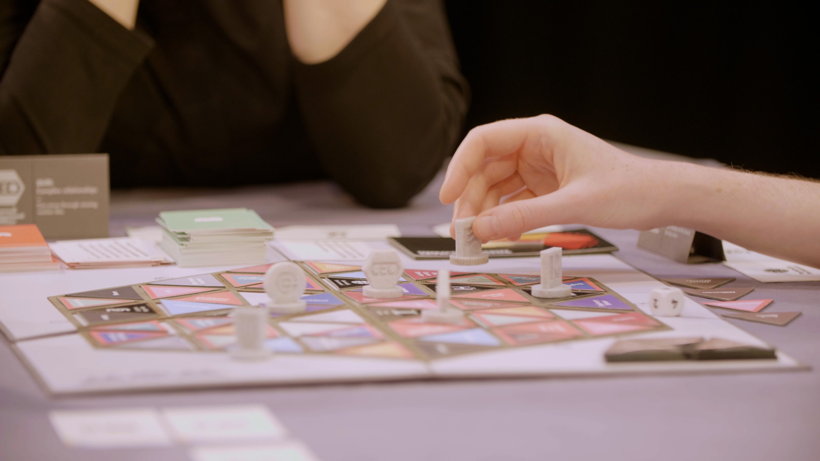 A close up photograph shows one hand moving a piece on the board.