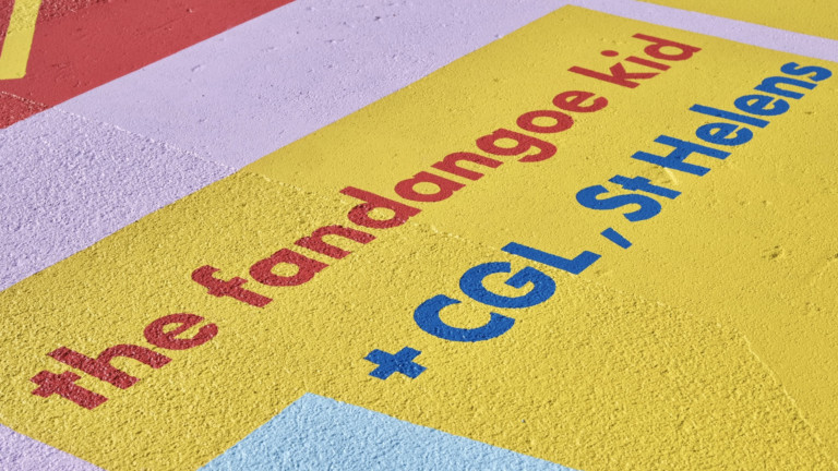 The words "The Fandango Kid and CGL, St Helens" are painted on the ground is bold colours