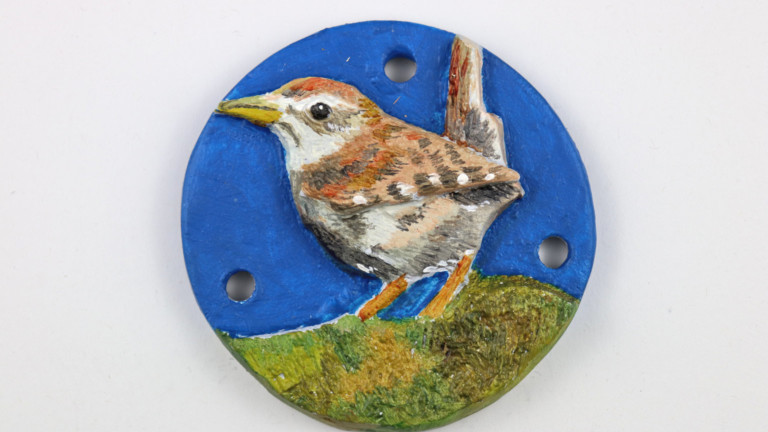 Photograph of a ceramic tile featuring a hand painted wren