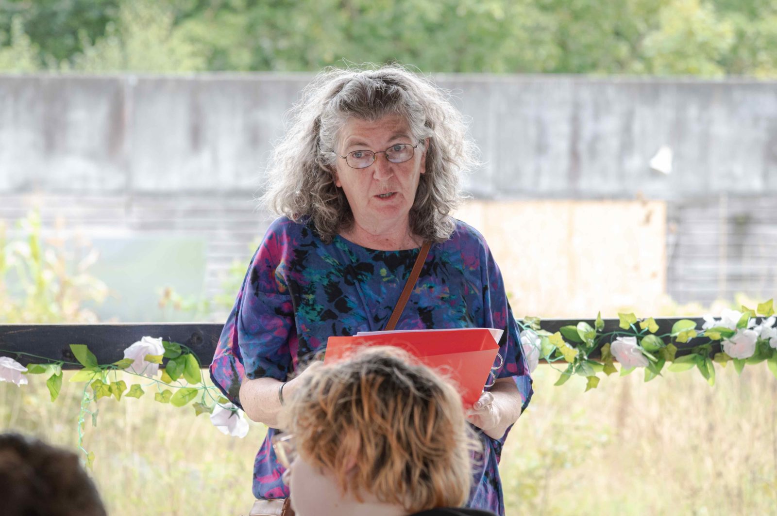 A participant of John Maguire's Parklife workshops reads a poem off a page in incredible edible community garden.