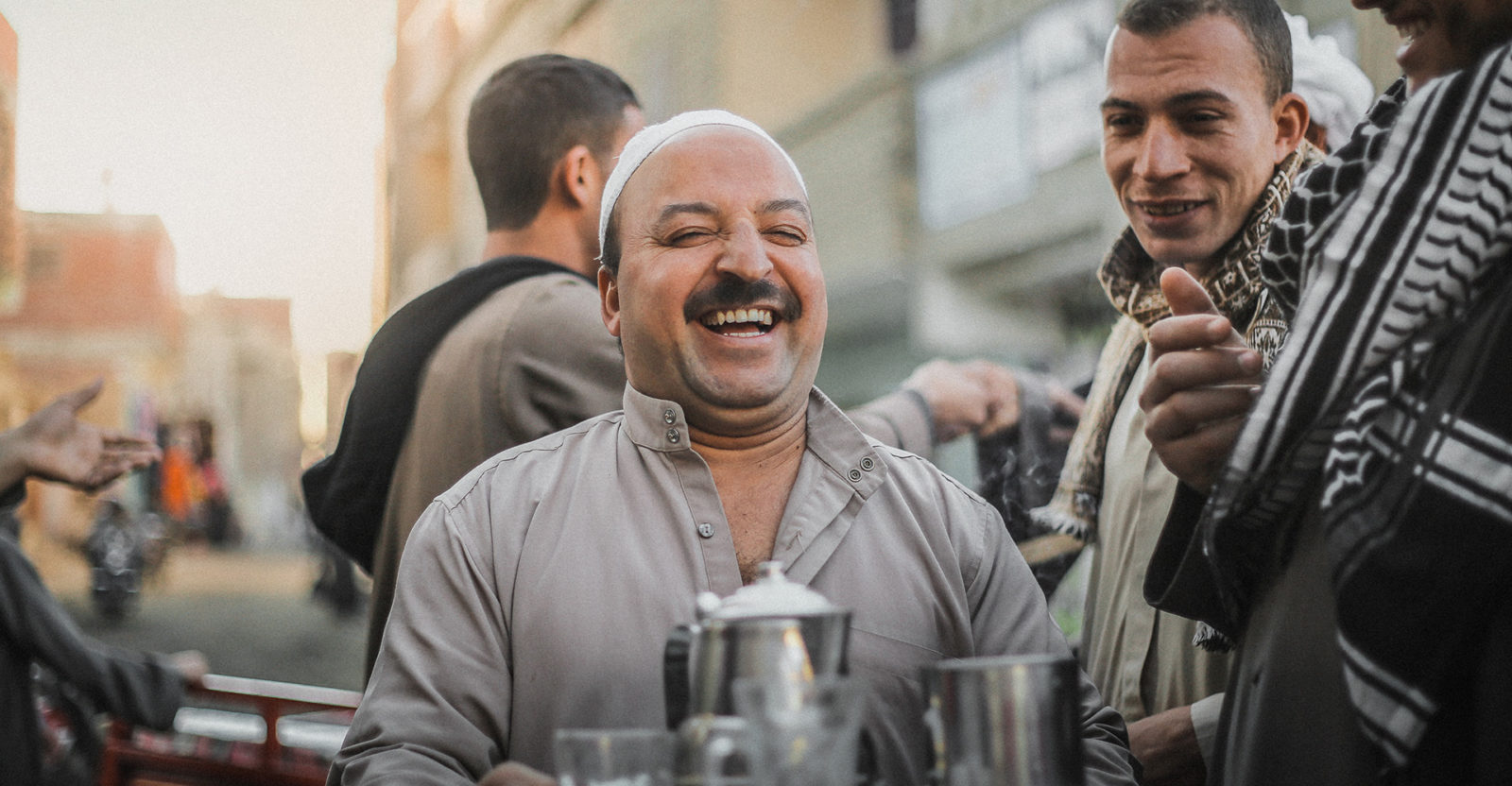 A man in Egypt laughing and holding a tray of drinks in a crowded street