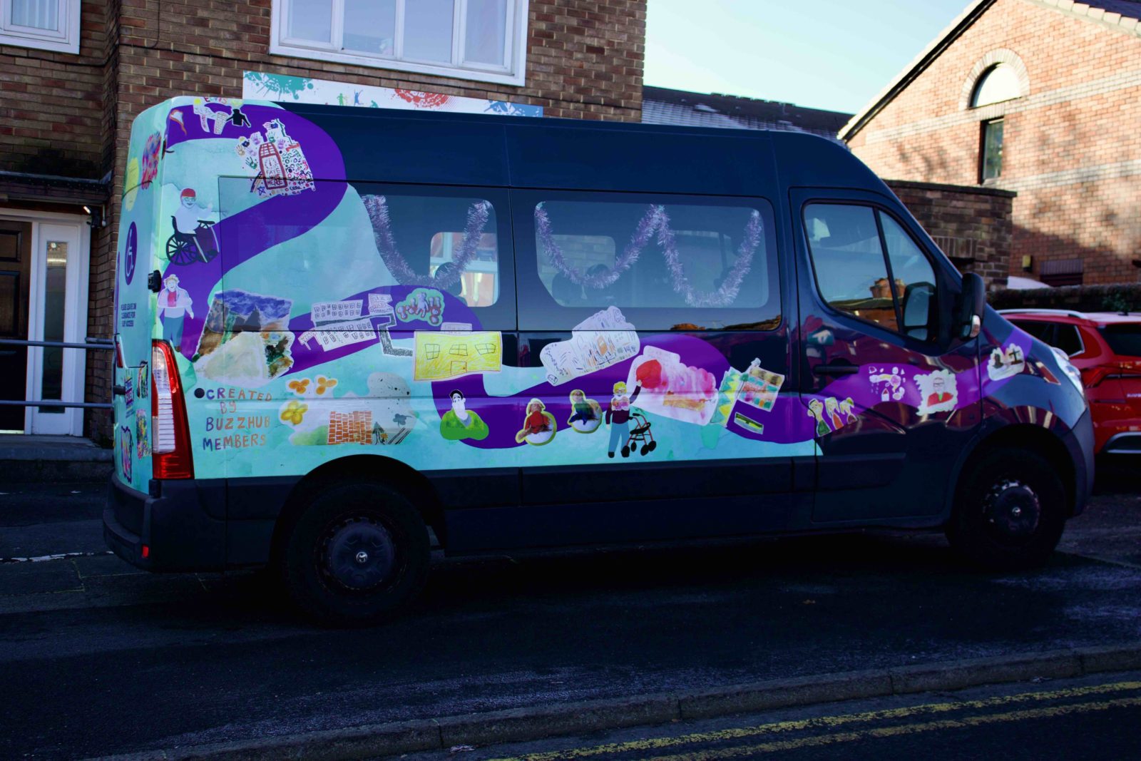 Buzz Hub bus with Rudy Loewe's vinyl wrap applied, it is mostly turquoise with a purple wiggly line wrapping around the bus with illustrations from the workshops dotted around it.