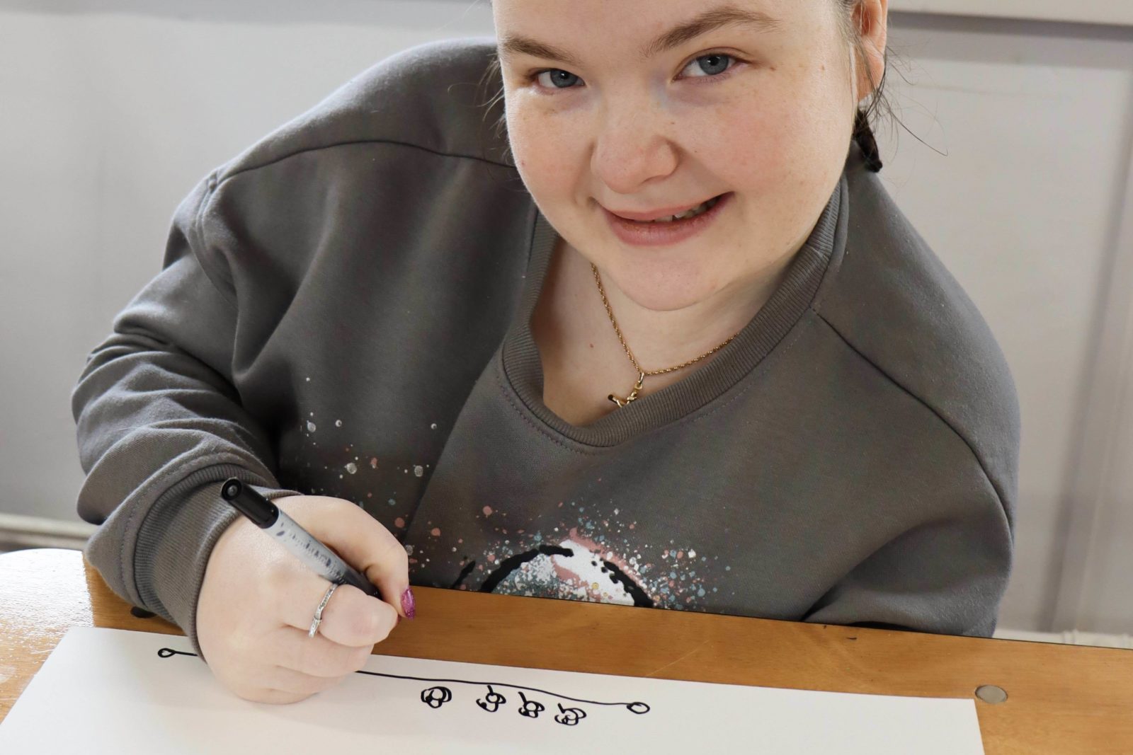 A Buzz hub member smiling a the camera whilst drawing a picture