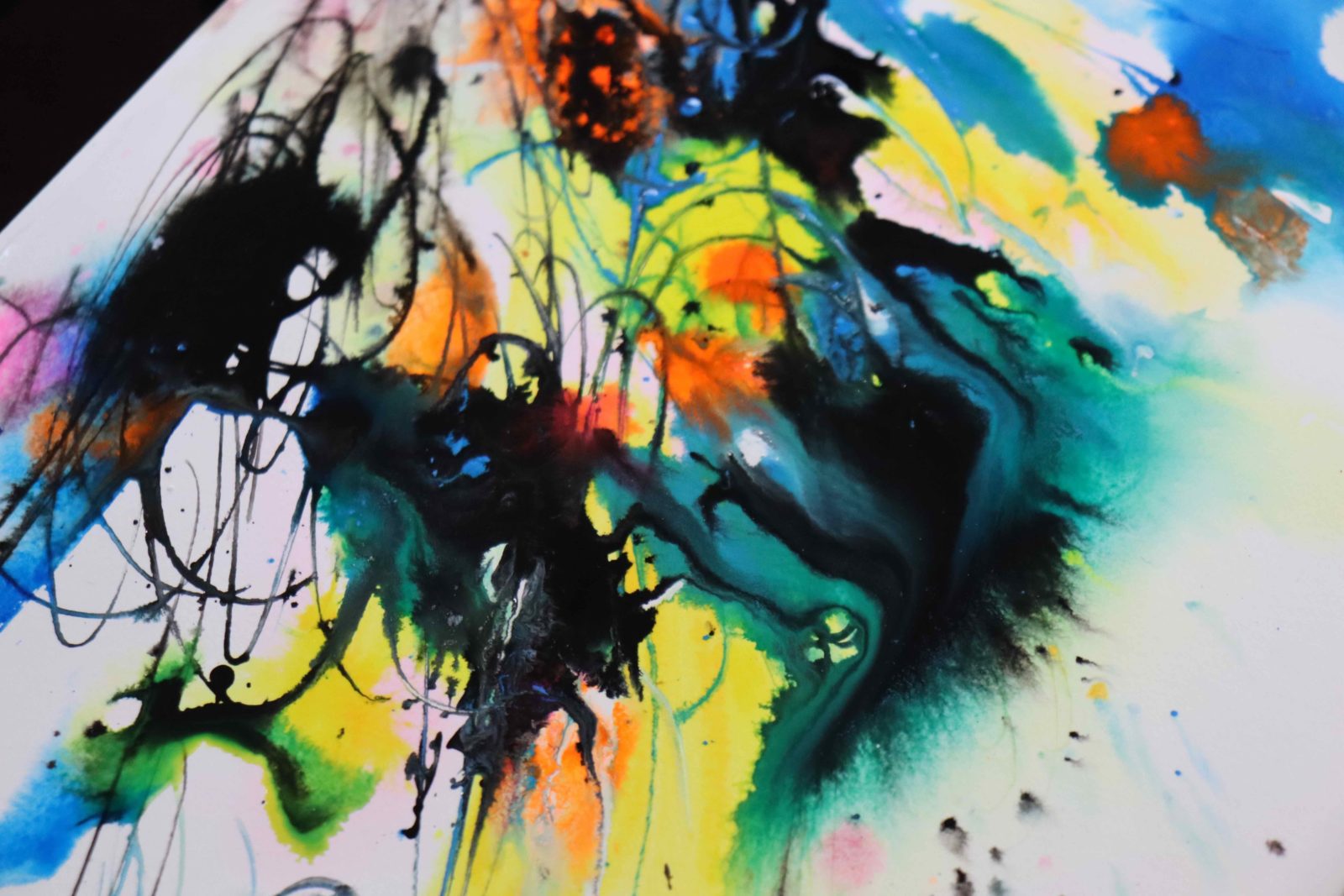 An abstract marble piece with black, blue, yellow and orange inks blending into each other.