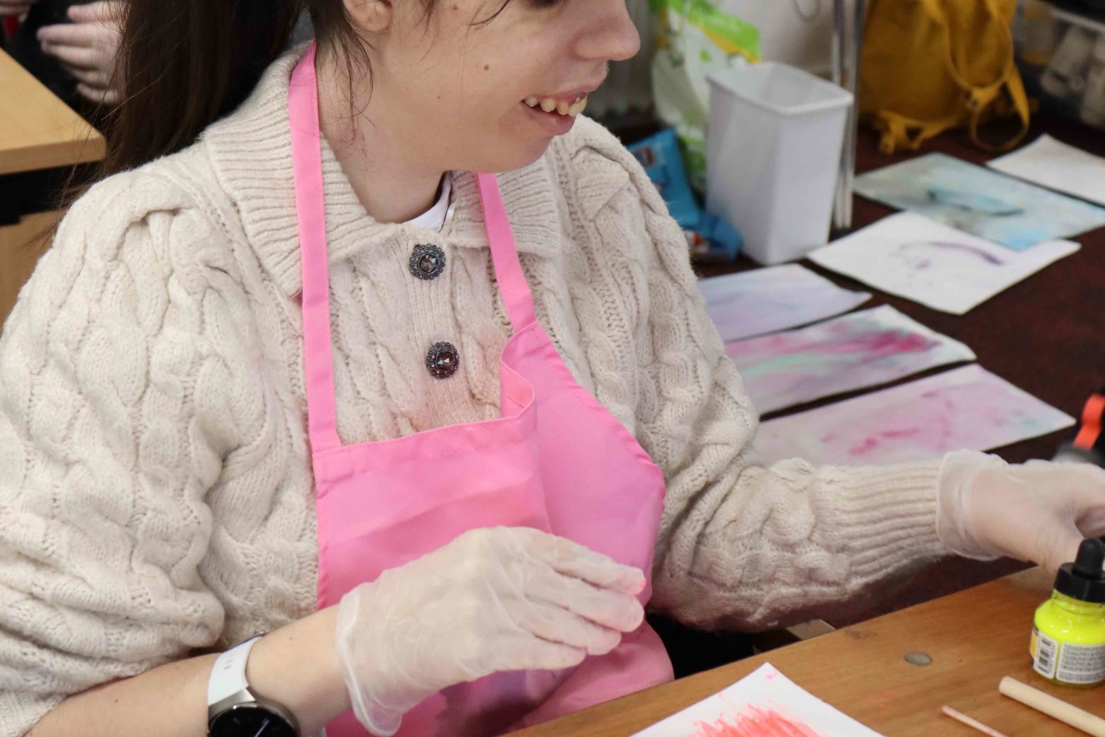 A Buzz Hub member experimenting with inks, wearing a pink apron and smiling as she works.