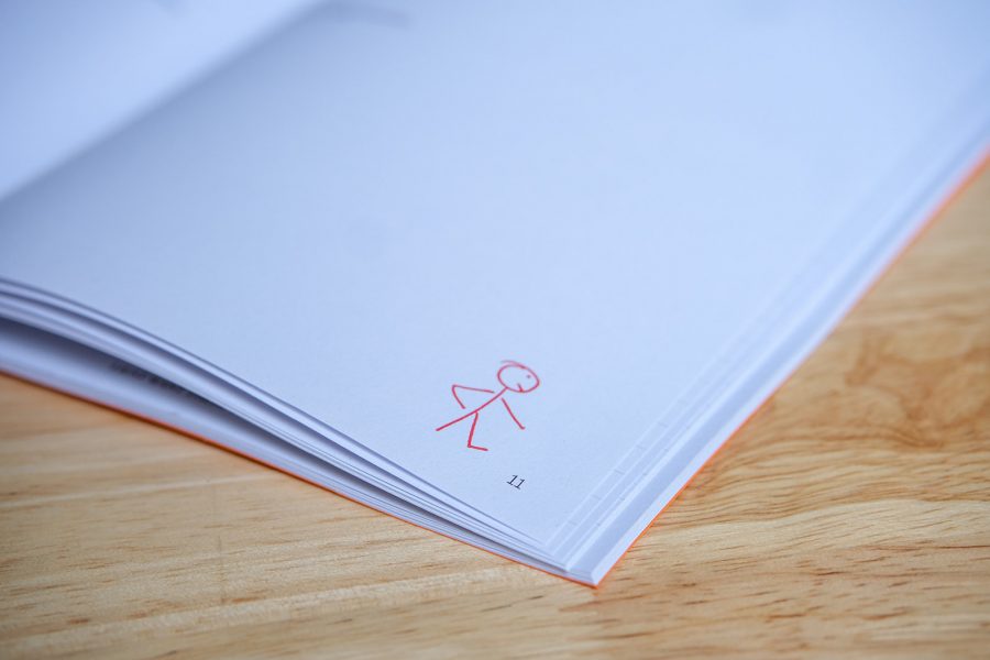 Internal pages of textbook. A stick figure is drawn in red pen in the corner of a white page.