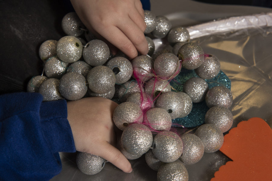 A cluster of silver glittery balls are tied together in to a string. A person is holding on to the balls.