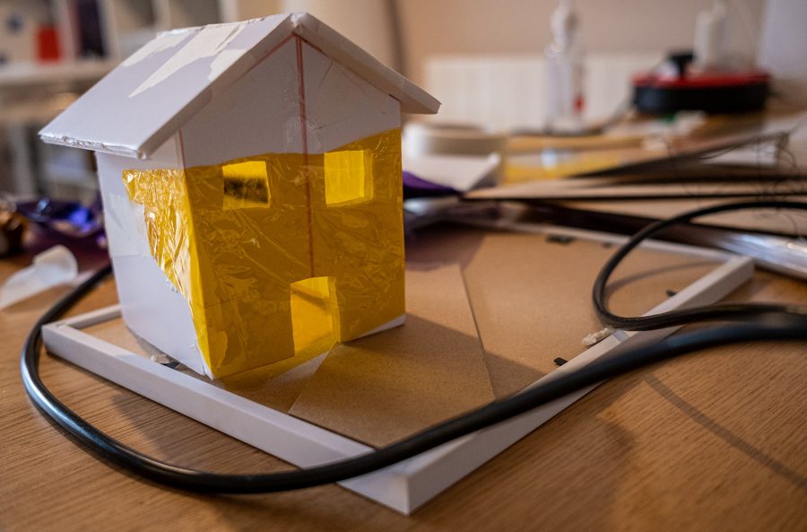 A small cardboard sculpture of a house with wires all around