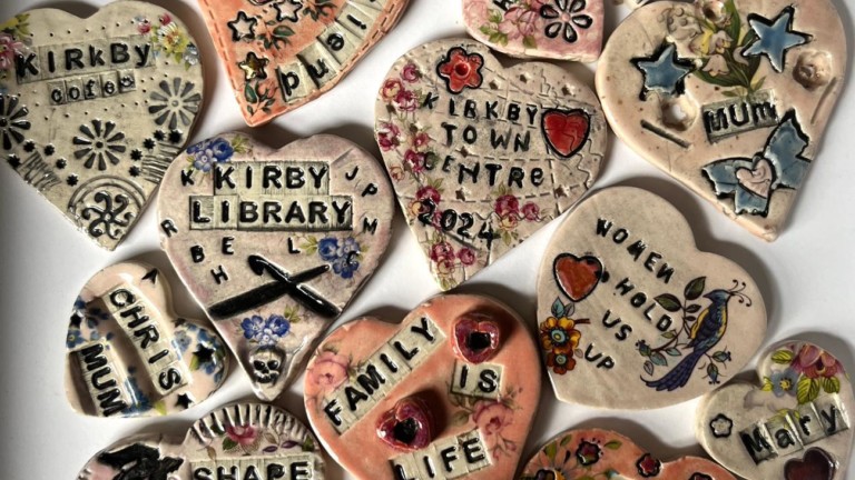 Photograph of a collection of clay hearts, each inscribed with a woman's name