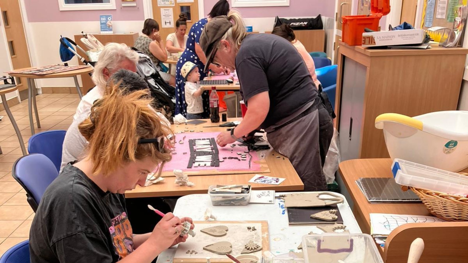 A group of adults around a table, making objects in a craft workshop